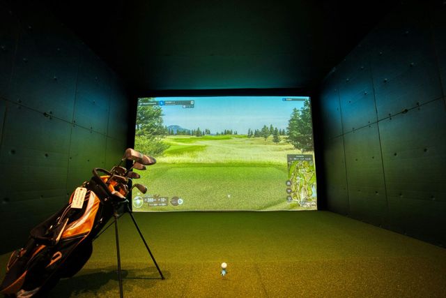 Indoor golf simulator with a golf bag facing a projected fairway